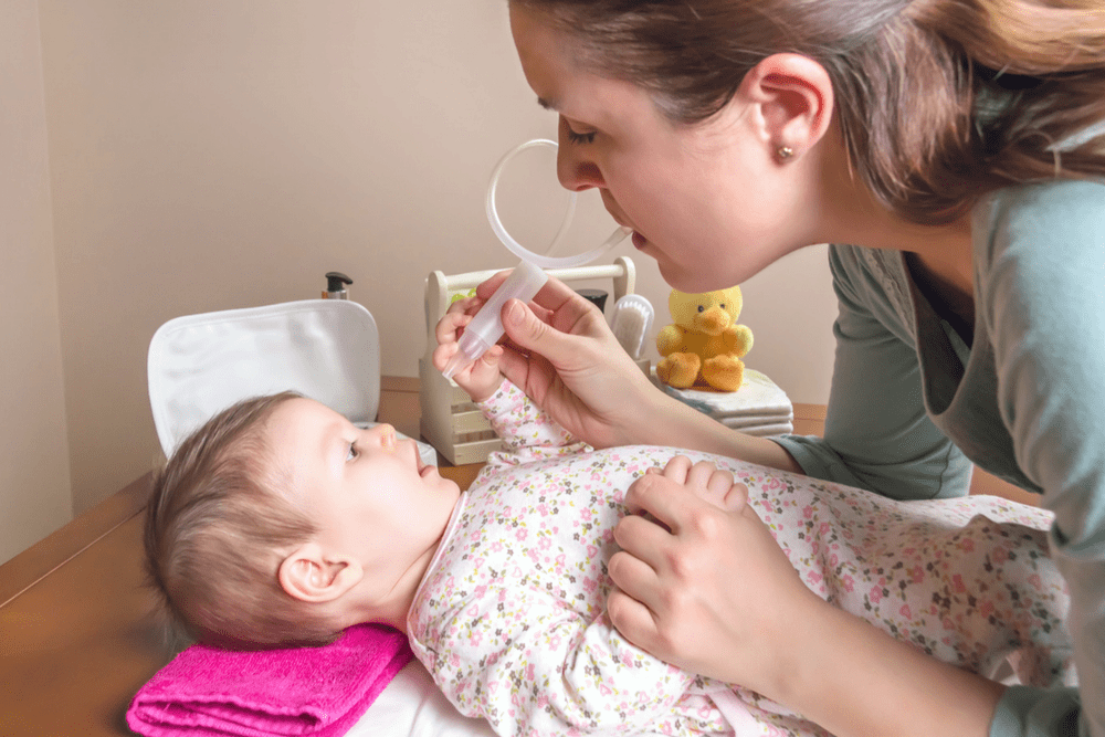 Using the nose frida to aspirate a baby's clogged nose.