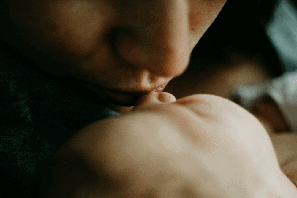 mother kissing baby postpartum depression
